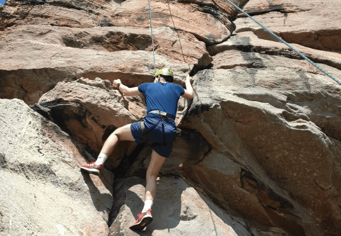 Rock climber ascending granite boulder in outdoor crag