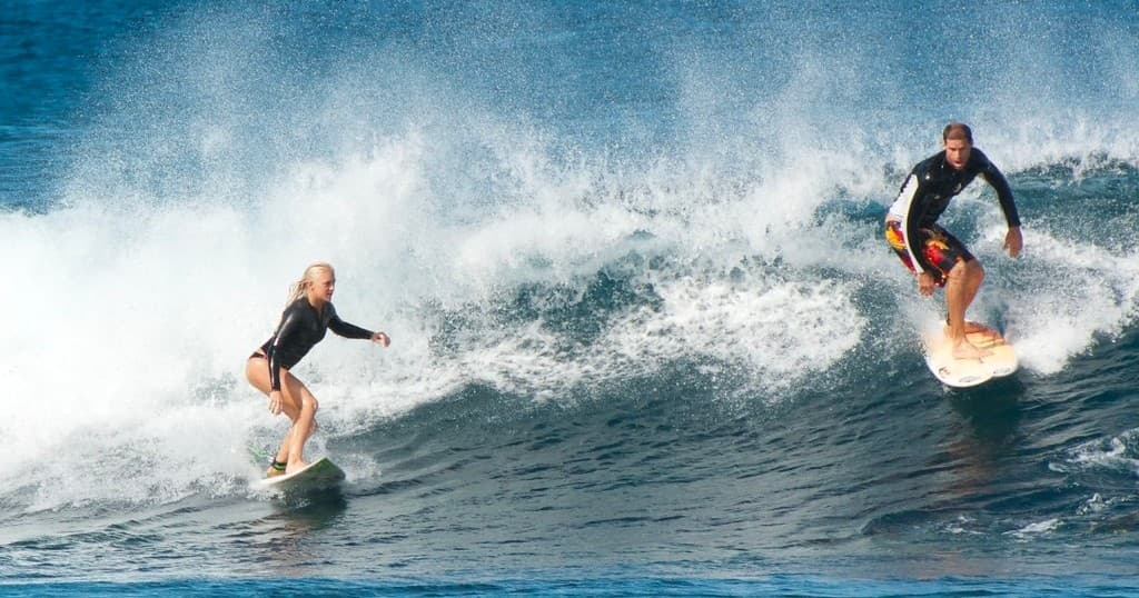 Surfers riding breaking waves on ocean reef near Hawaiian coast