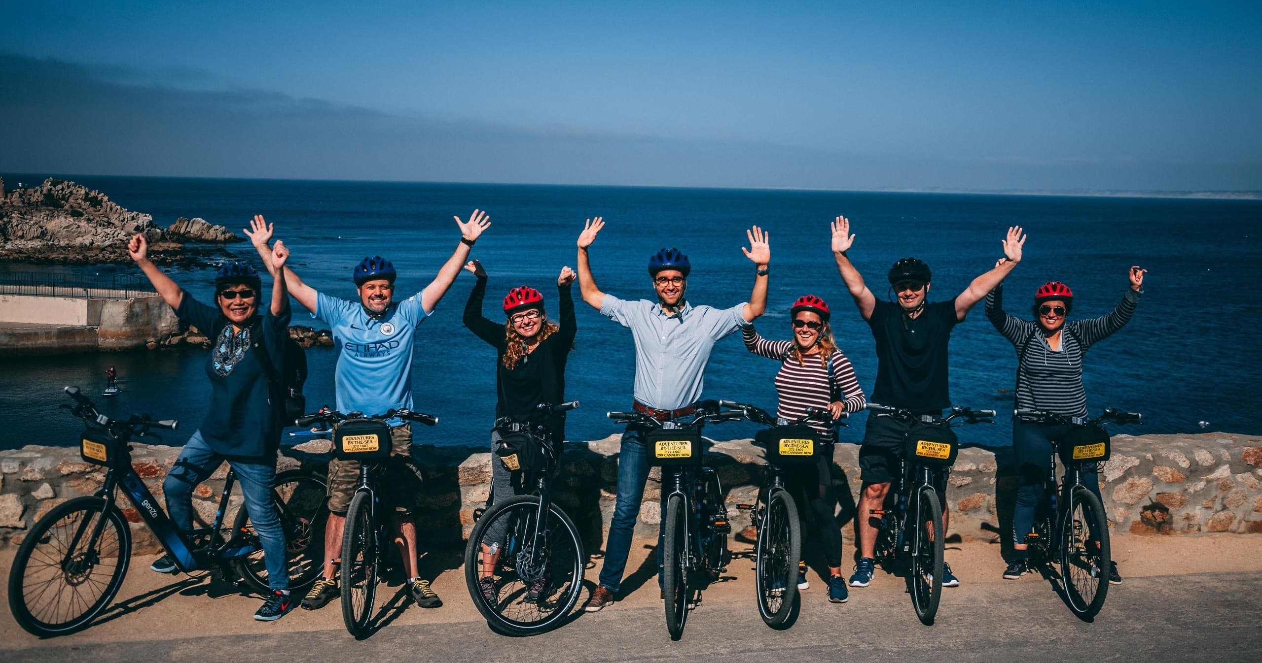 Group coastal bike tour riding along ocean bluff at sunset