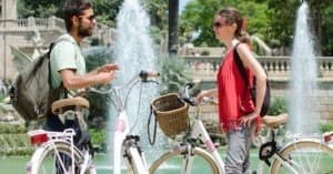 Couple talking by fountain with rental bikes in Barcelona park
