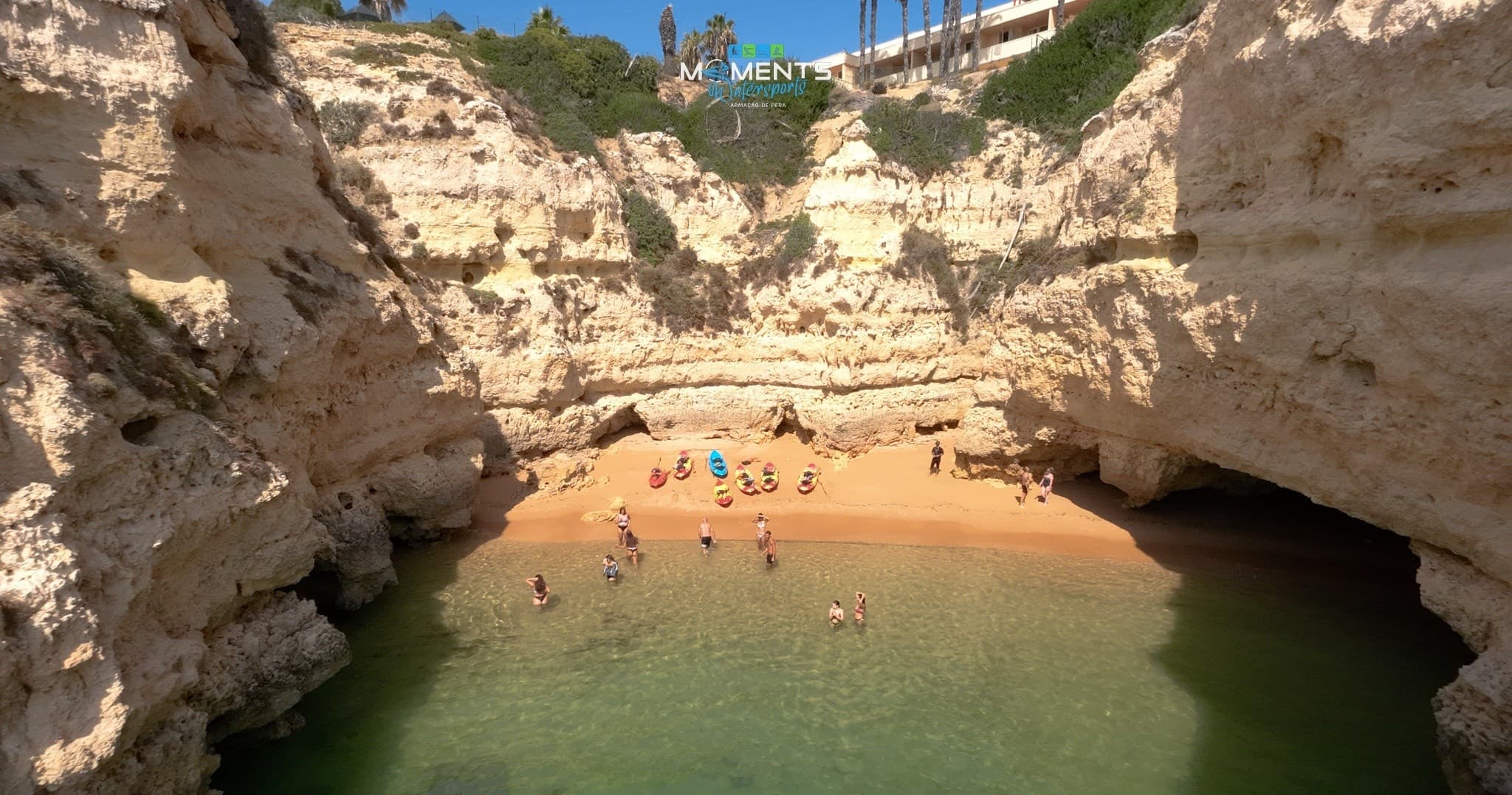 Hidden sandy cove surrounded by cliffs with swimmers