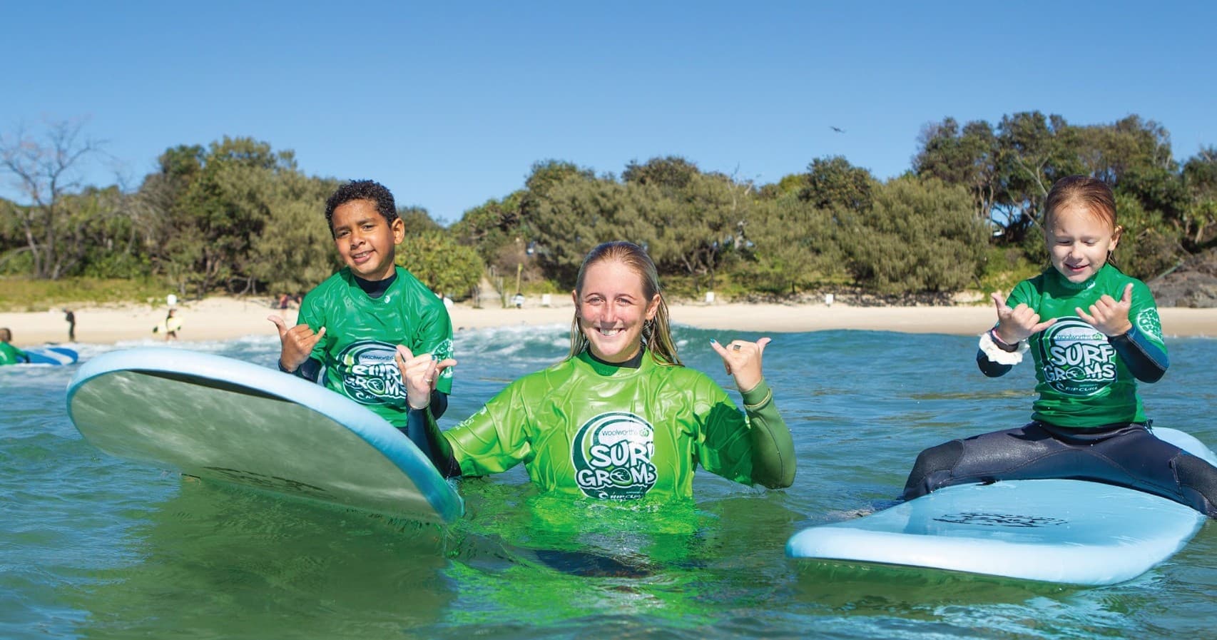Three young surfers smiling on soft boards in calm sea