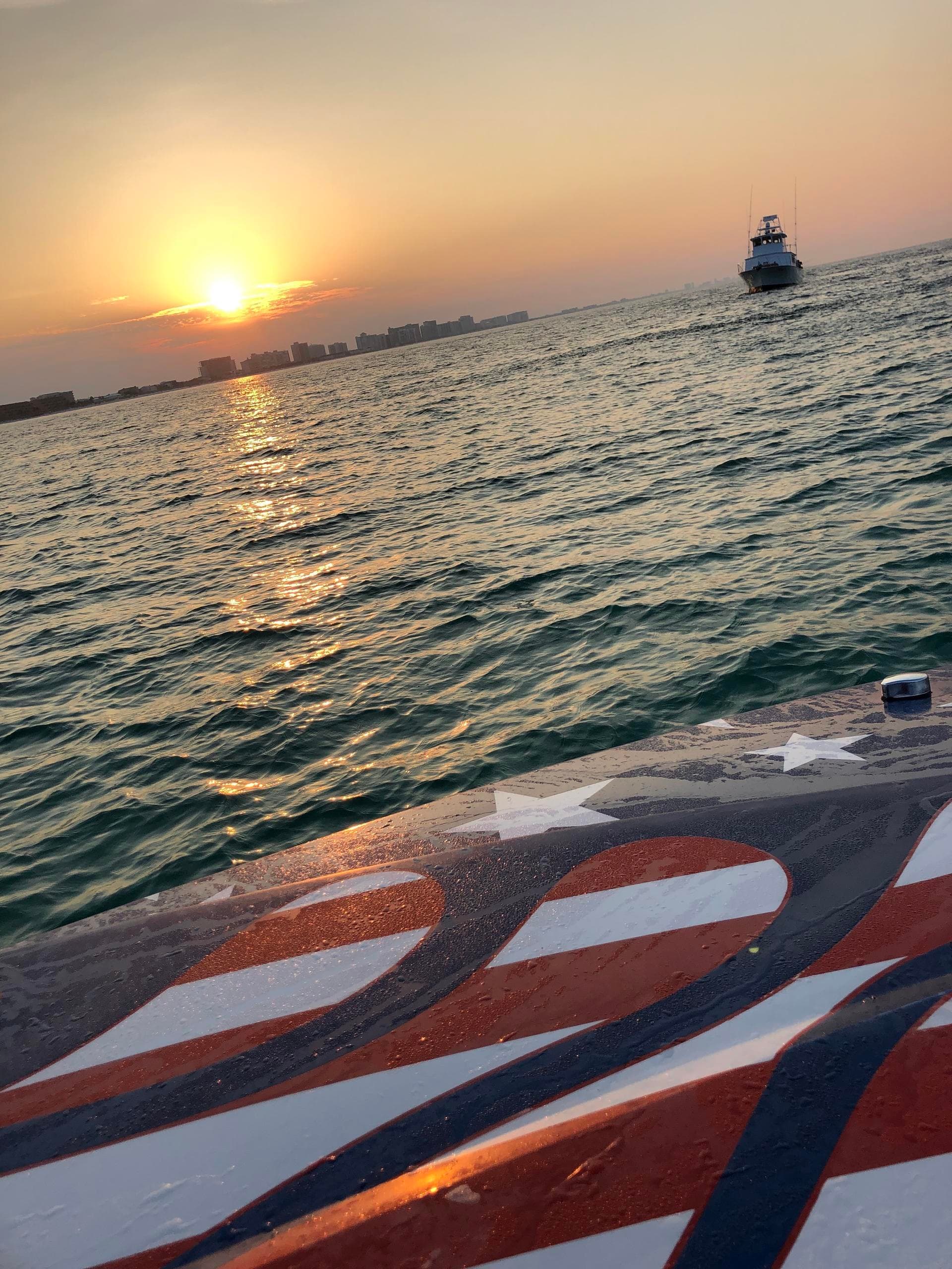 Golden sunset over ocean from boat bow with ferry in distance