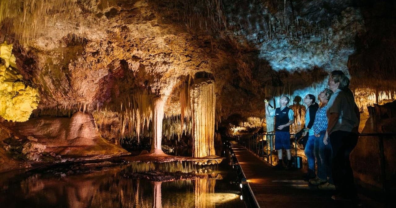 Illuminated cave walkway with stalactites on guided cave tour