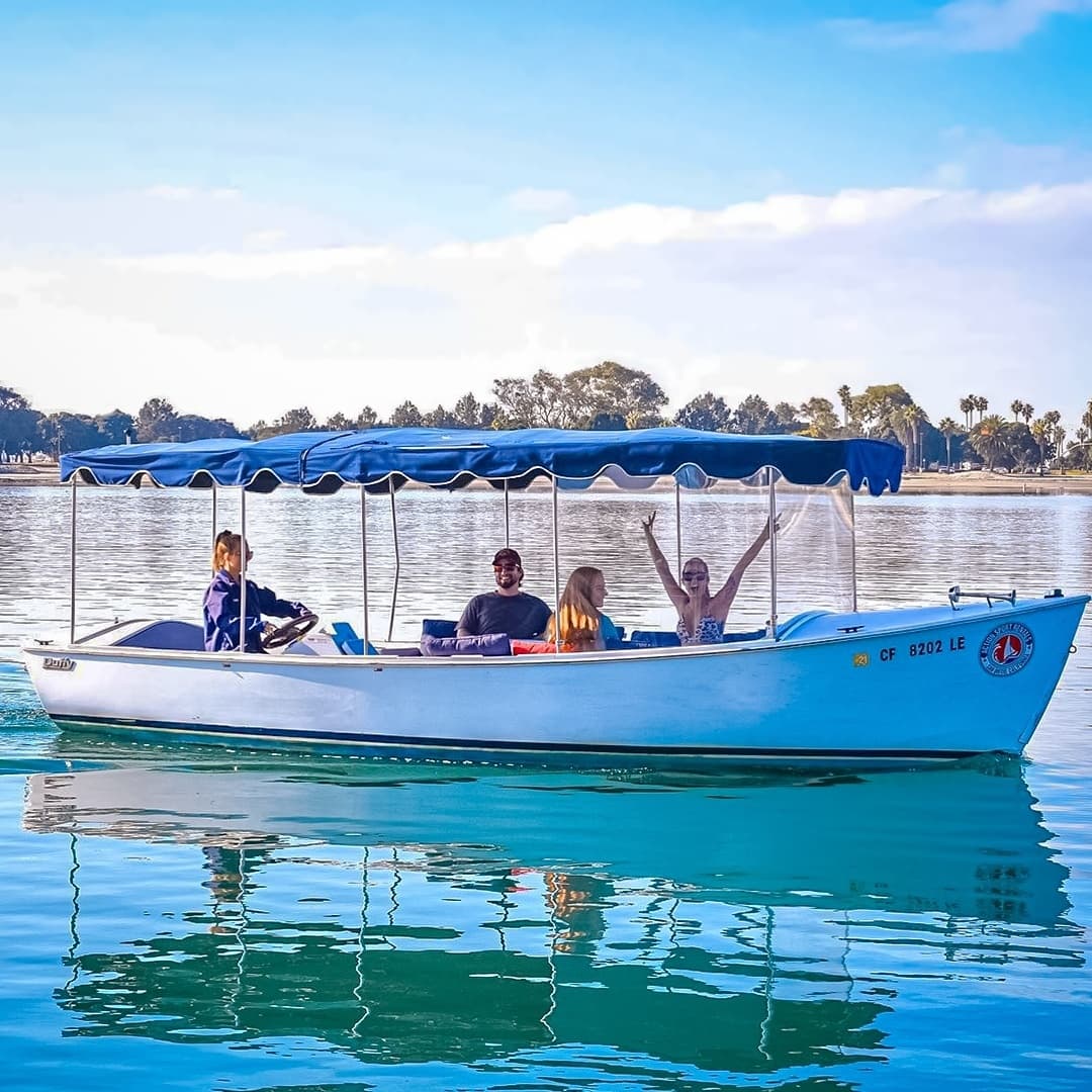 Small tour boat with passengers cruising calm bay, guided outing