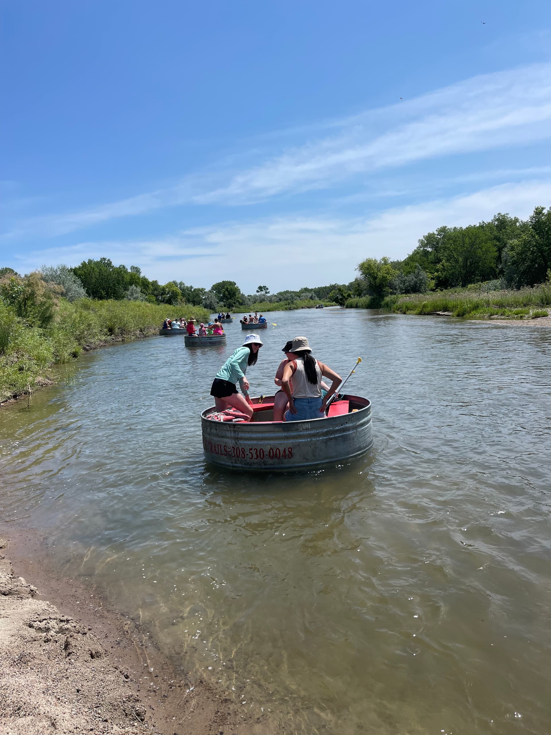 Round-tub river float with paddlers on shallow prairie river
