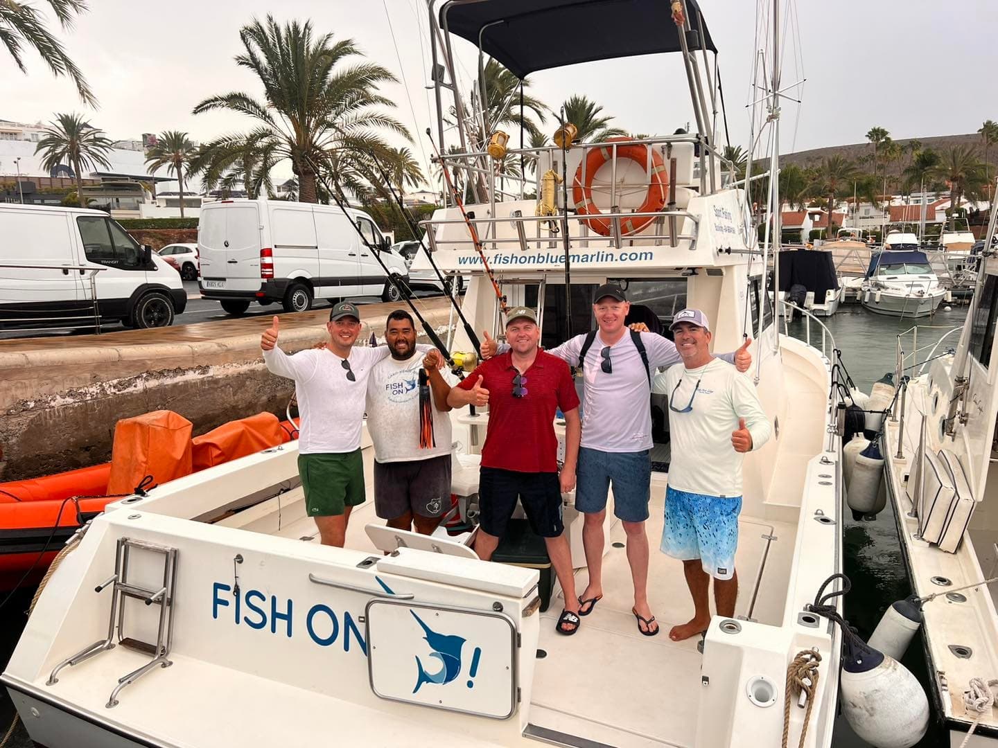 Group of anglers at docked charter Fish On boat, marina backdrop