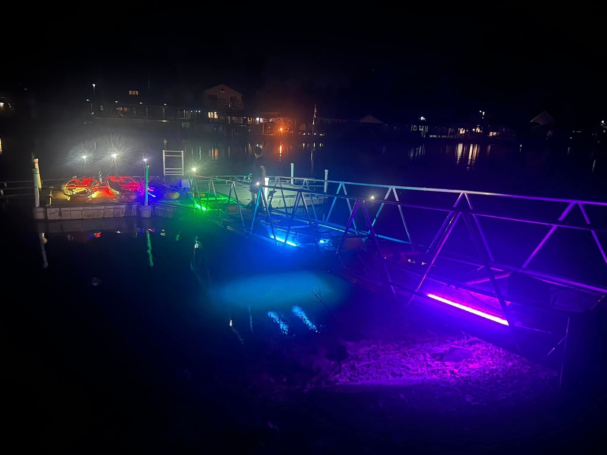 Dock with colorful underwater LED lights at night on lake