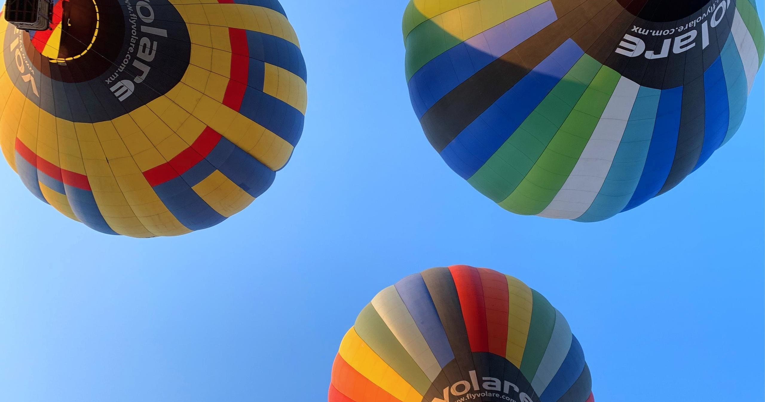 Three colorful hot air balloons floating over blue sky, group flight