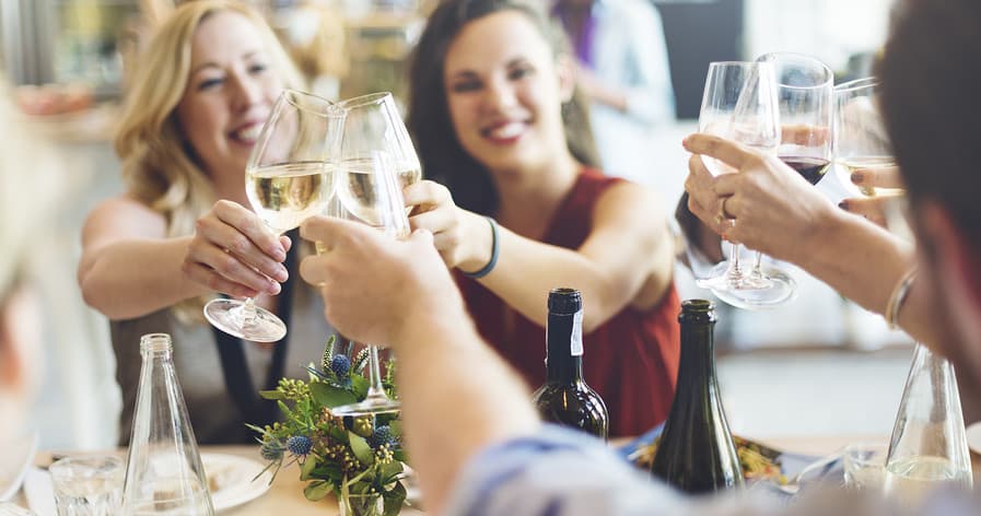 Friends toasting wine at indoor food tour dining table