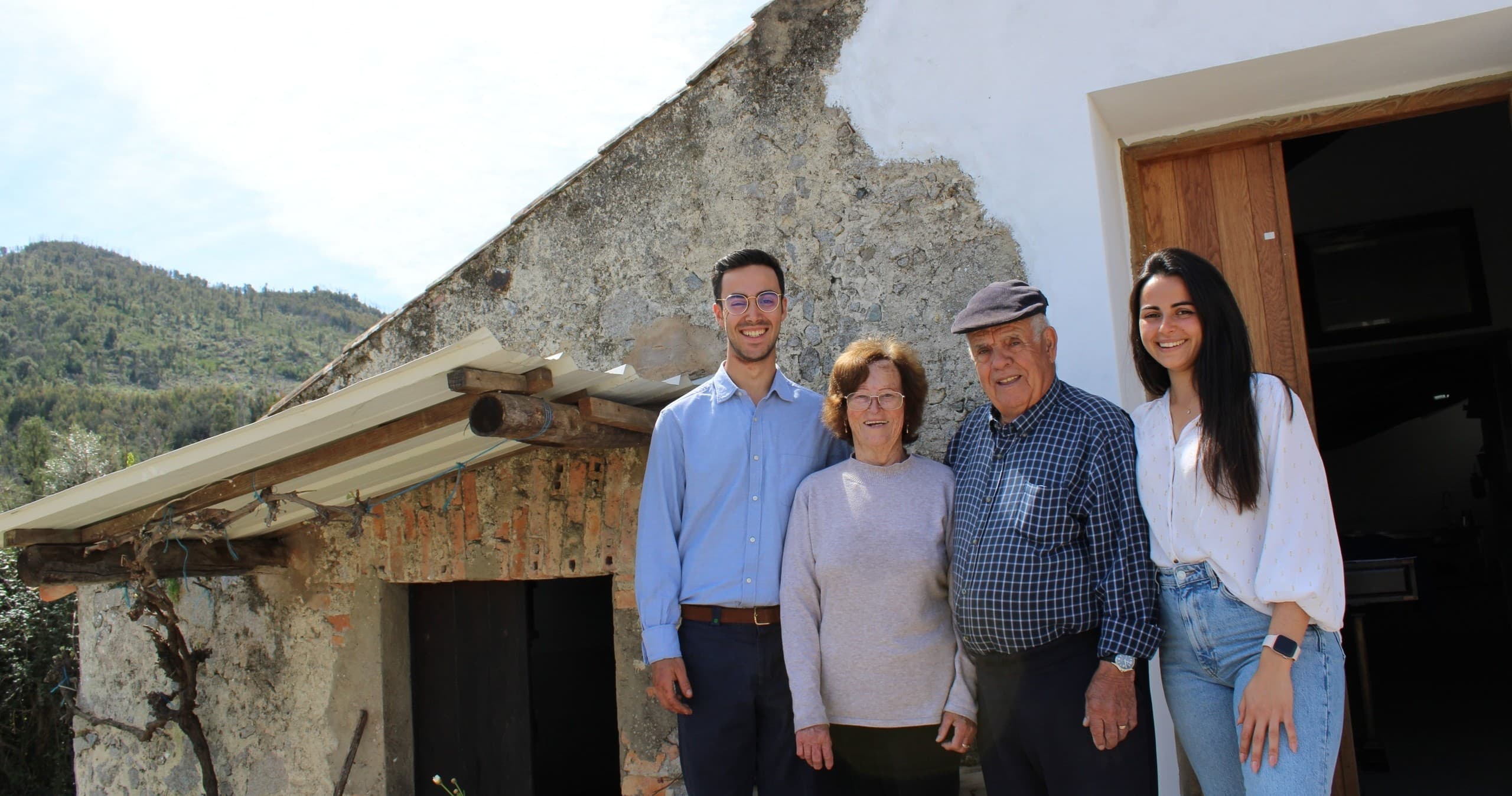 Family standing outside rustic olive farmhouse in countryside
