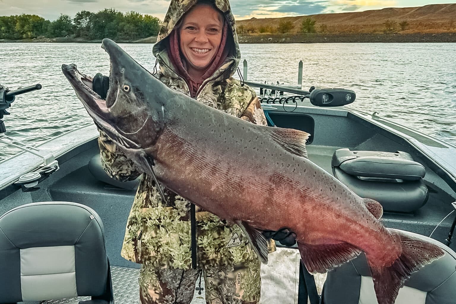 Angler holding giant king salmon on boat during river trip
