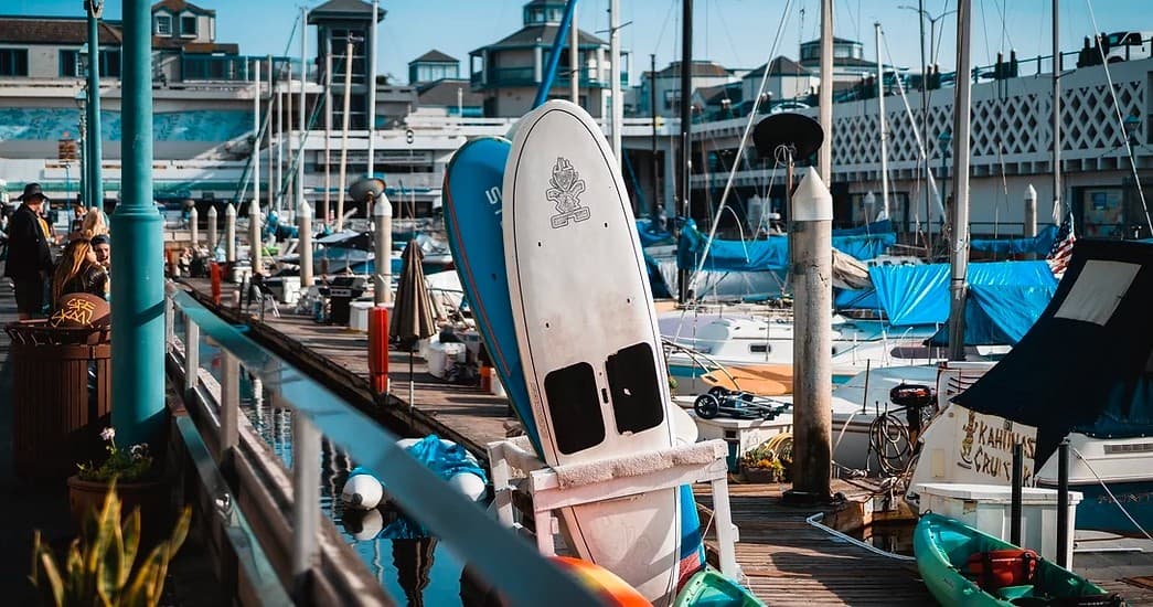 Standup paddleboards and boats lined along busy marina dock