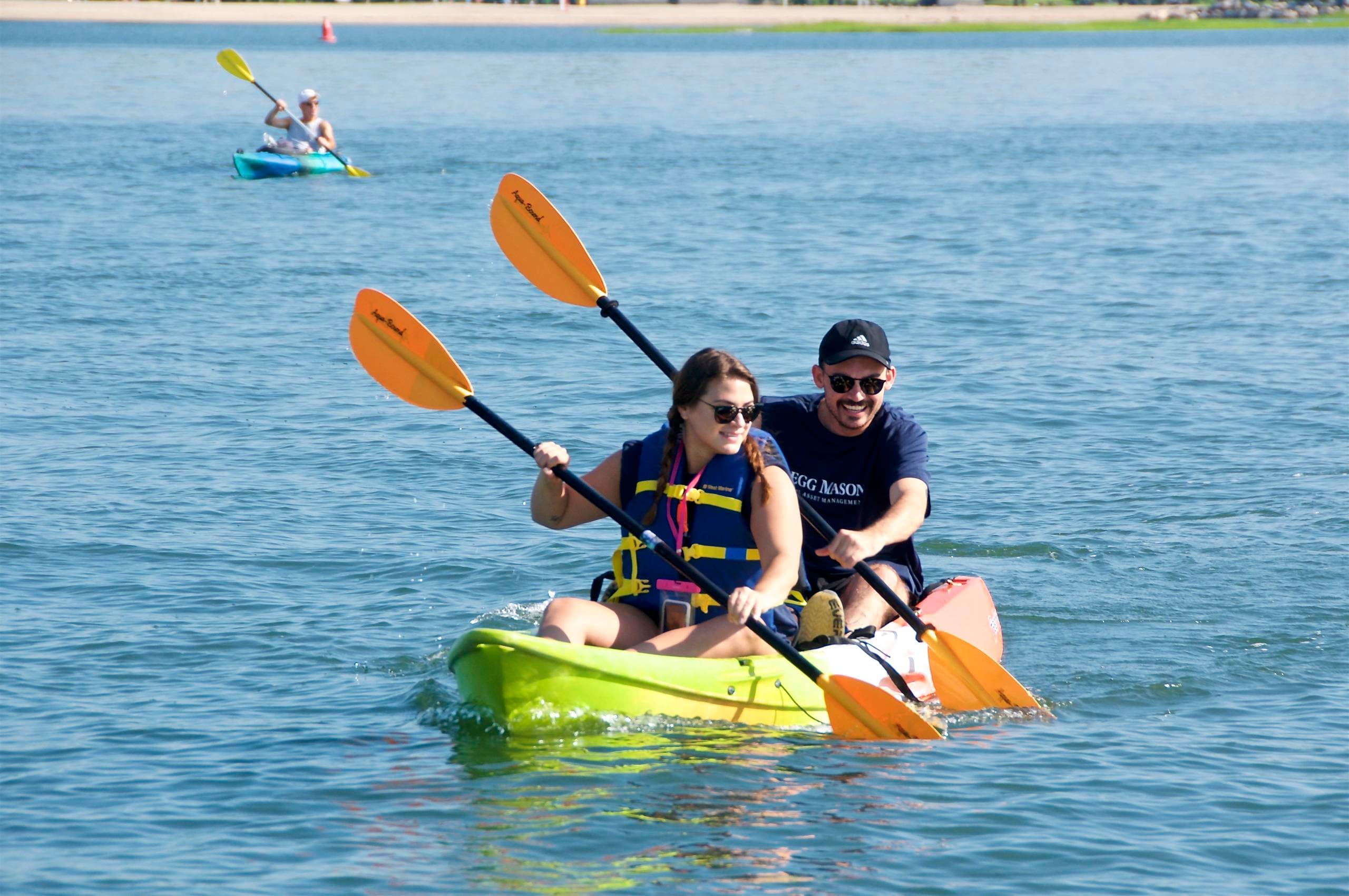 Two-person kayak paddling on calm bay waters near shore