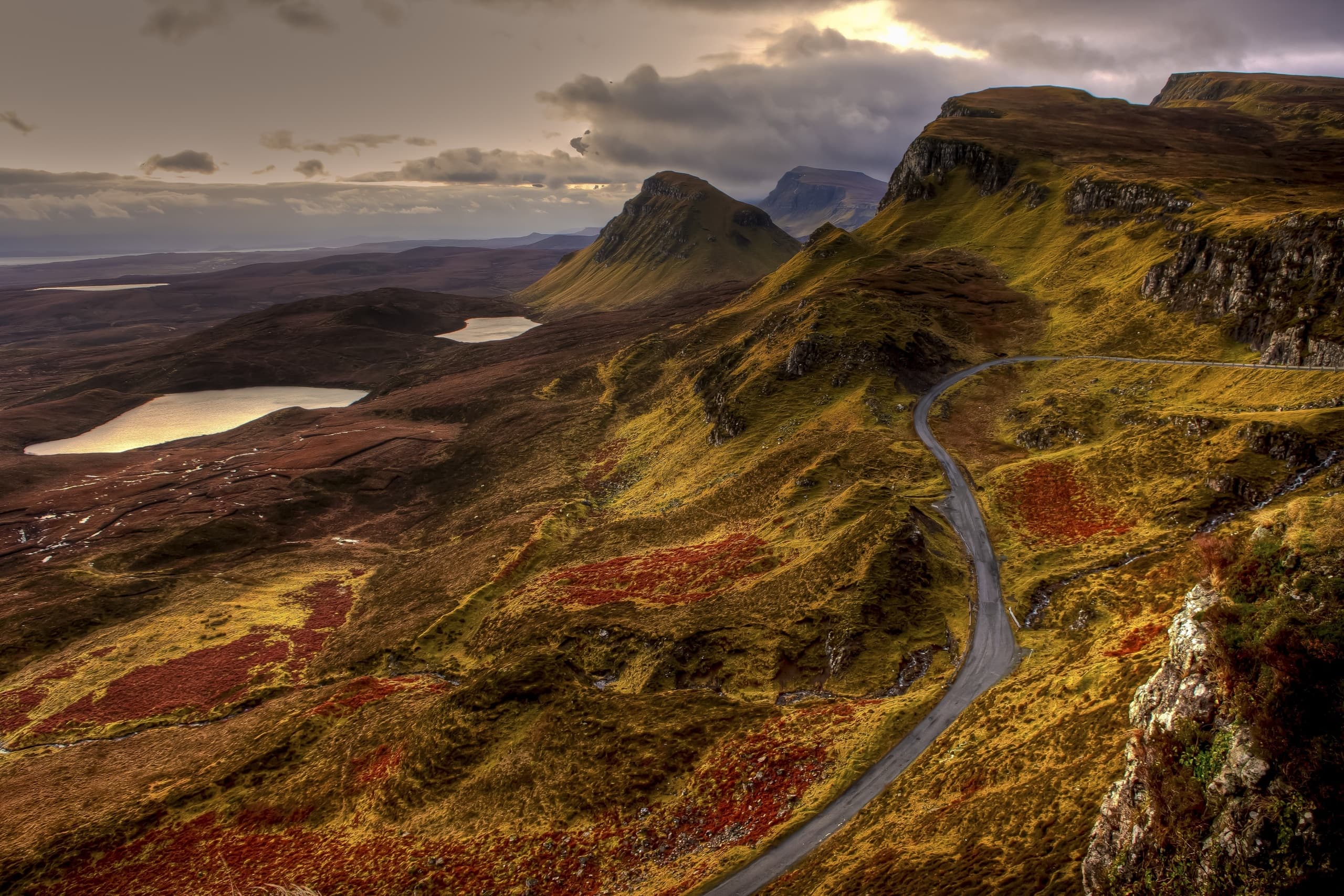 Winding road through rugged Scottish highlands at golden light