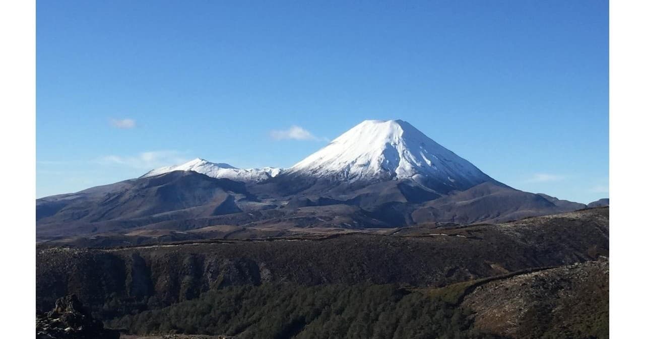 Snow-capped volcanic peak rising above alpine tussock and plains