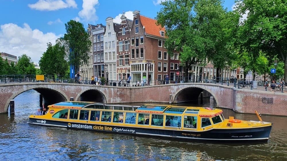 Amsterdam canal boat passing historic bridge on city cruise