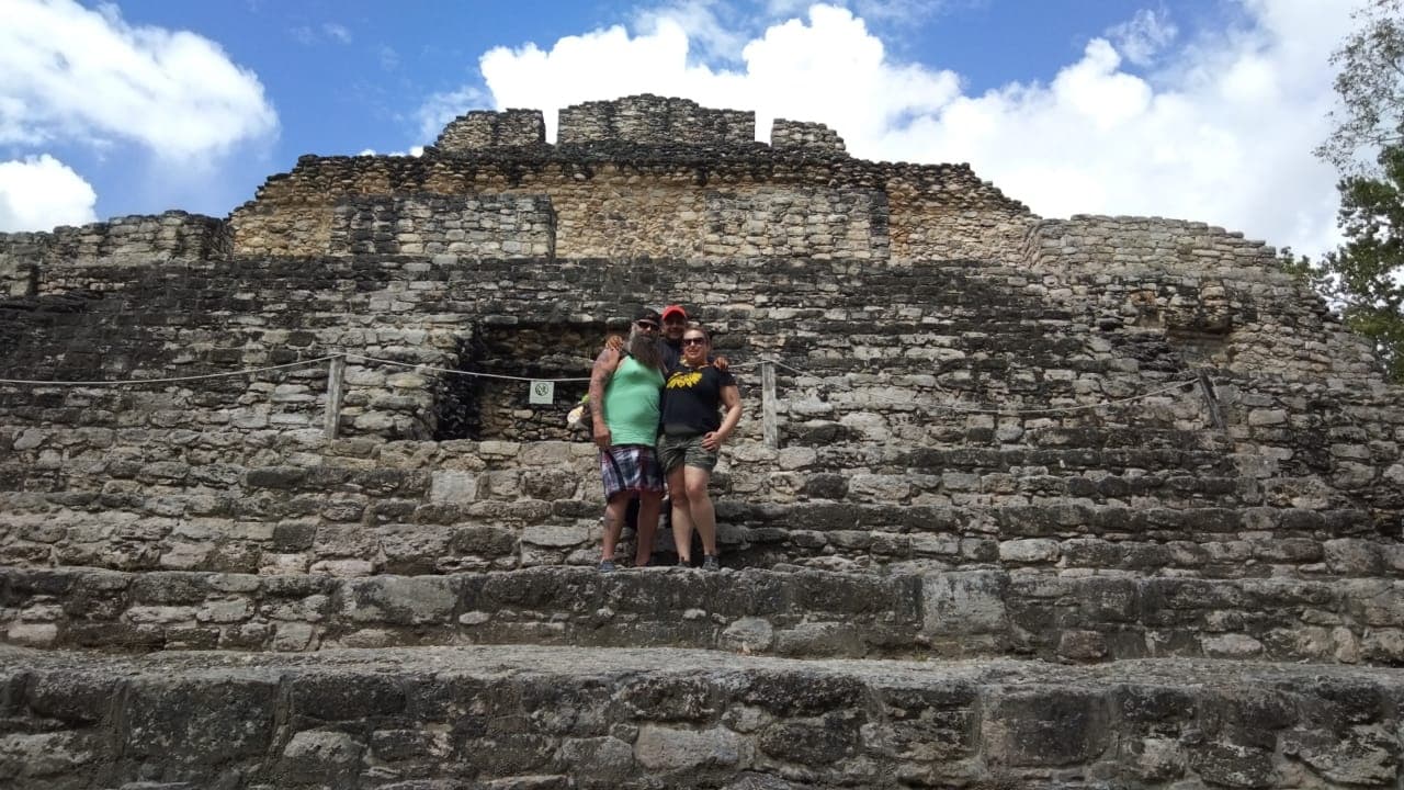 Visitors posing on stone steps at coastal Mayan archaeological site
