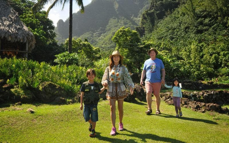 Family hiking through lush tropical valley on guided trail