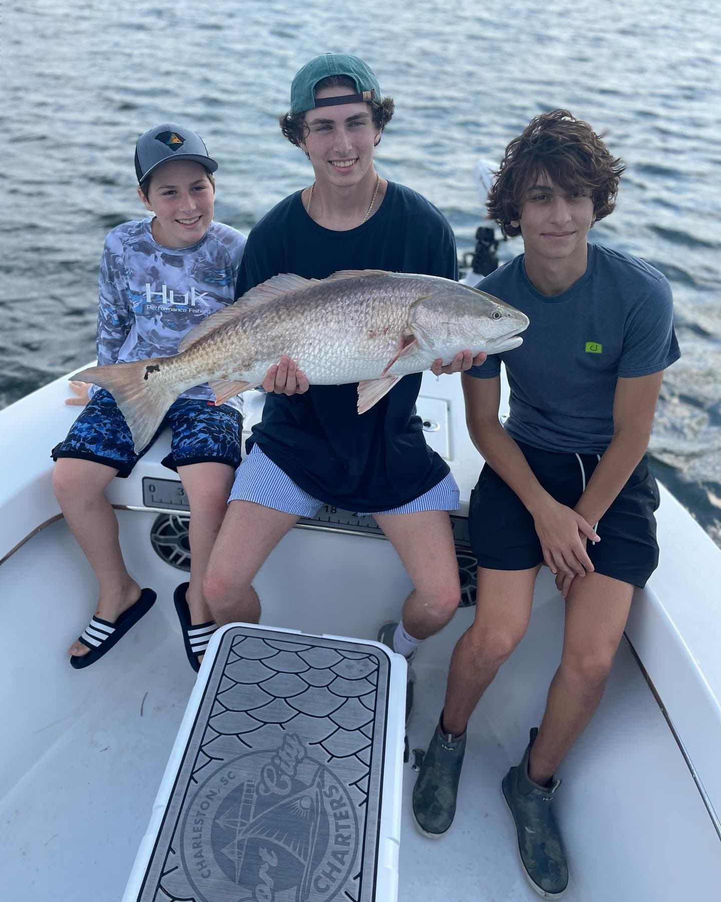 Three young anglers displaying big red drum aboard small boat