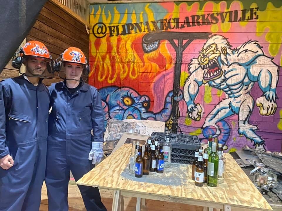 Two people in indoor axe-throwing venue with graffiti mural