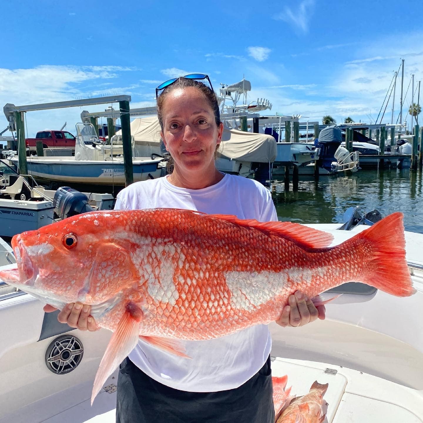 Angler holding trophy red snapper on boat at marina dock