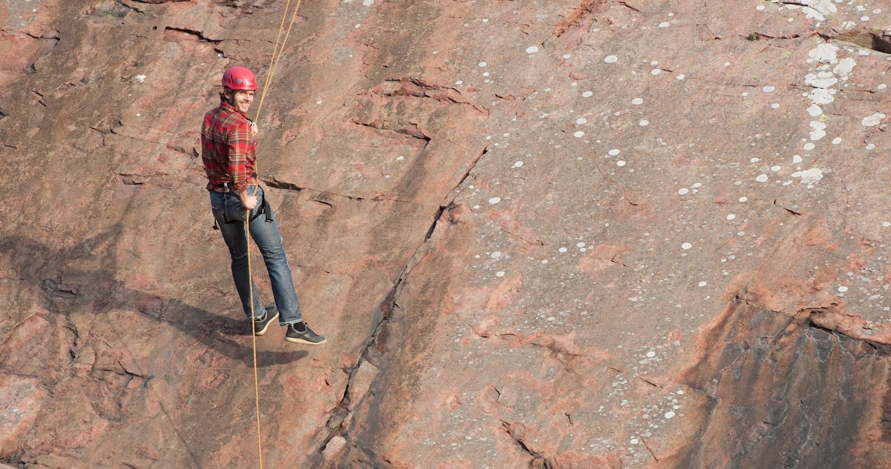 Rock climber ascending steep coastal cliff face on outdoor climb