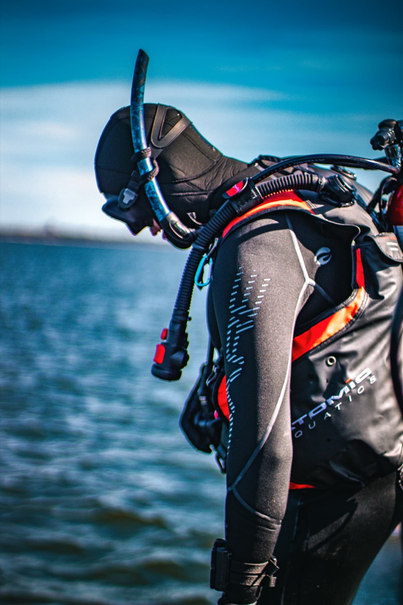 Wetsuit diver gearing up at shoreline before open-water dive