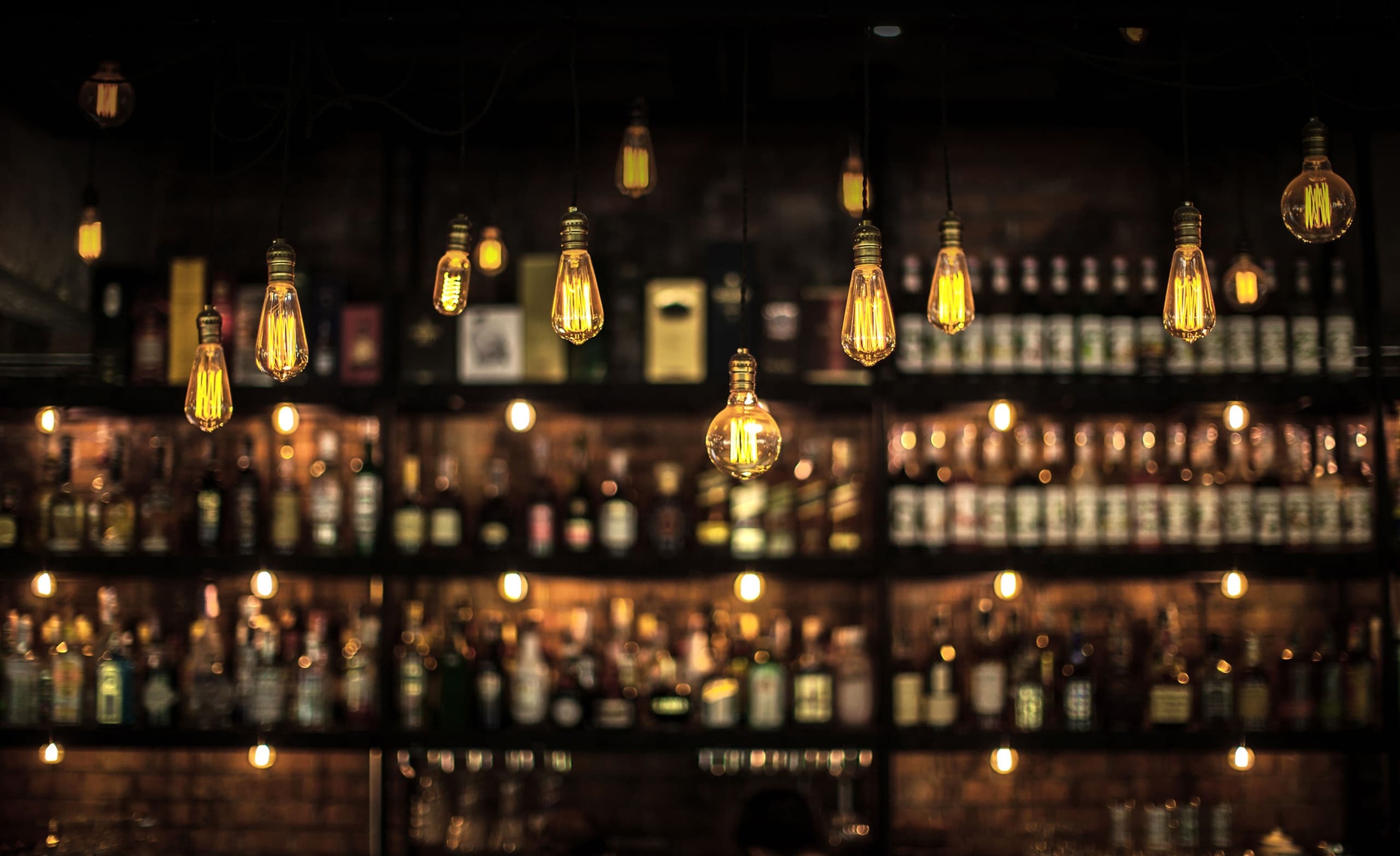 Warm bar interior with hanging Edison bulbs and liquor shelves