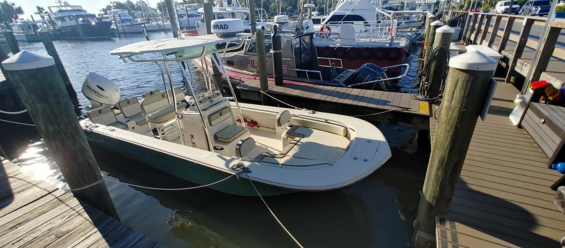 Small fishing boat docked at marina pier with urban waterfront