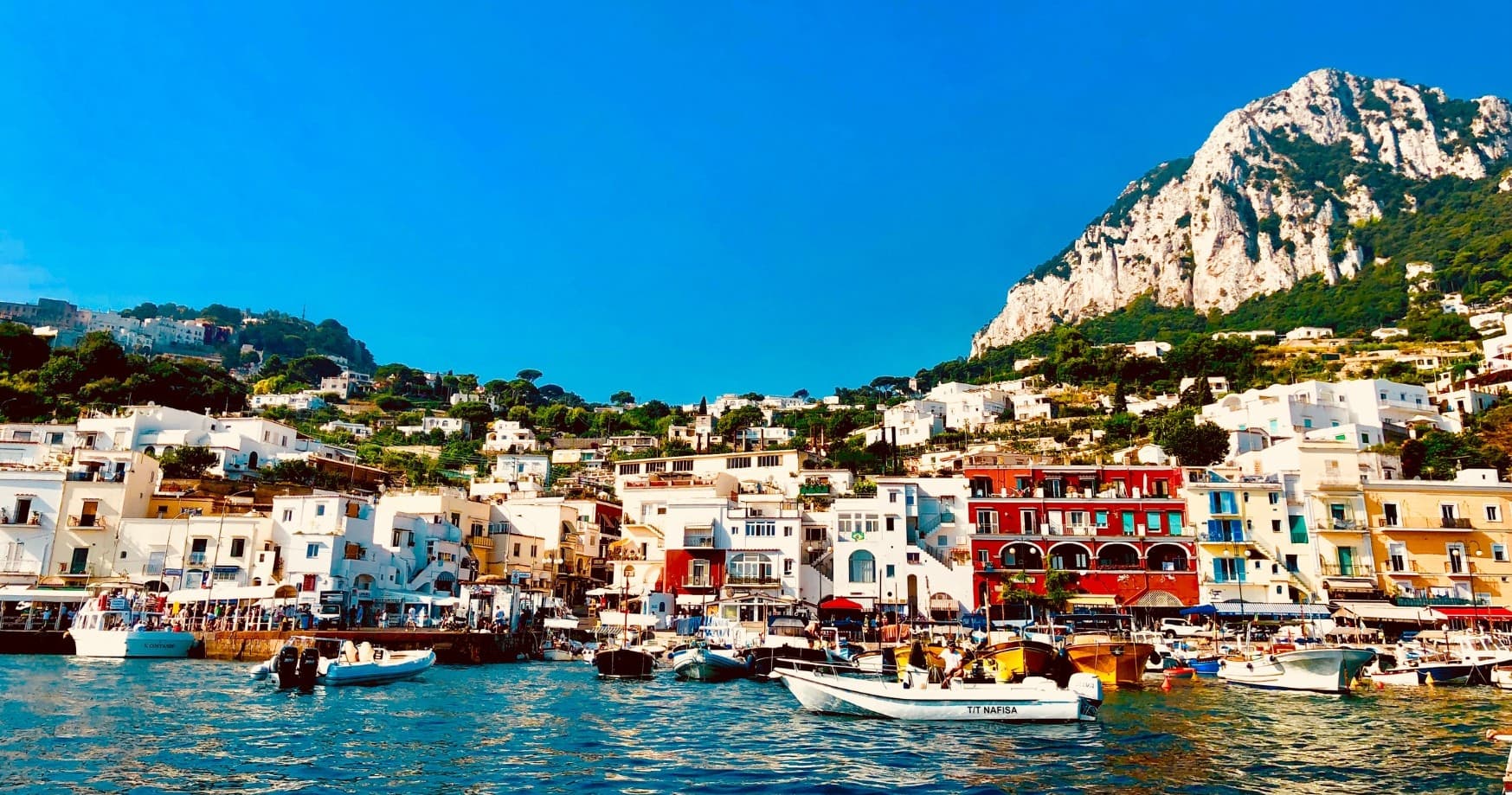 Colorful Positano harbor scene from sea with boats and cliff houses