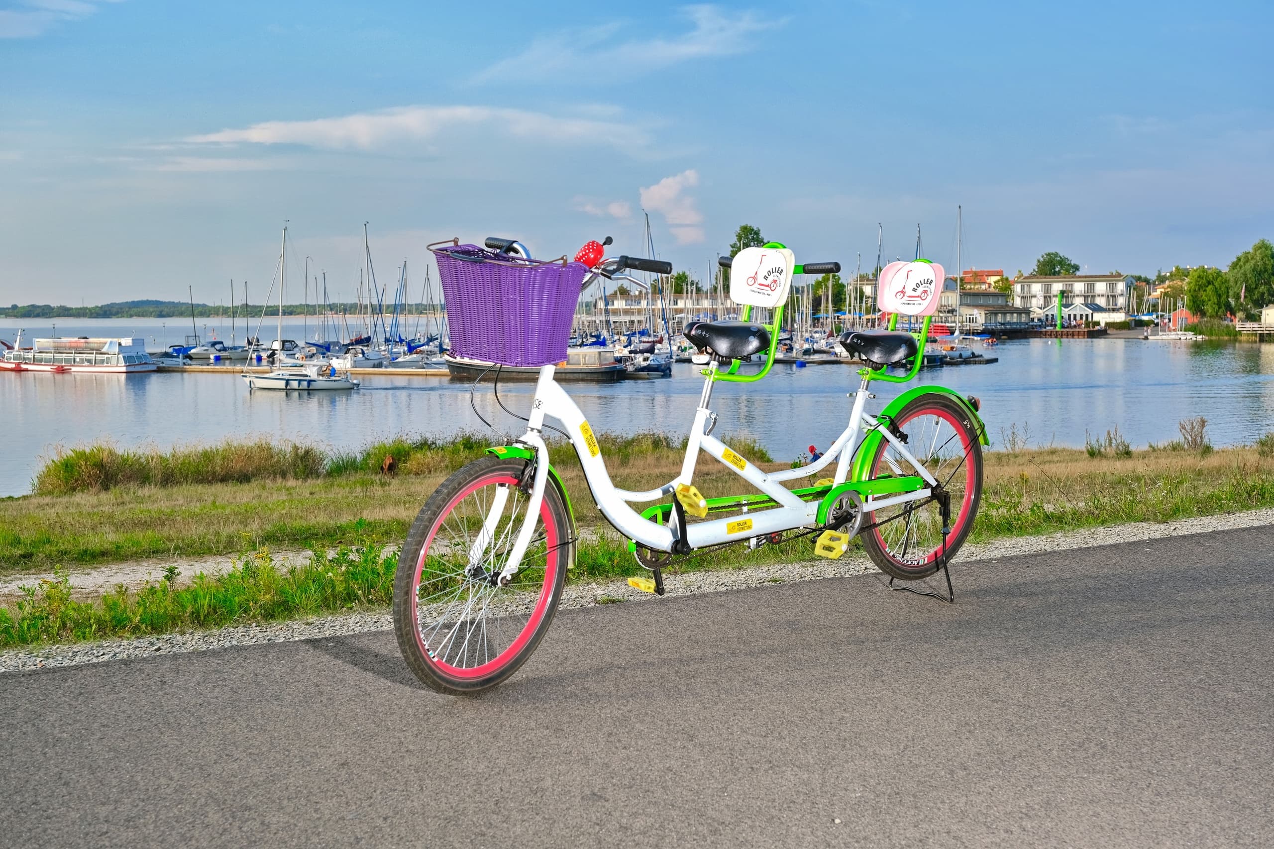 Tandem bicycle parked by marina with boats and waterfront view