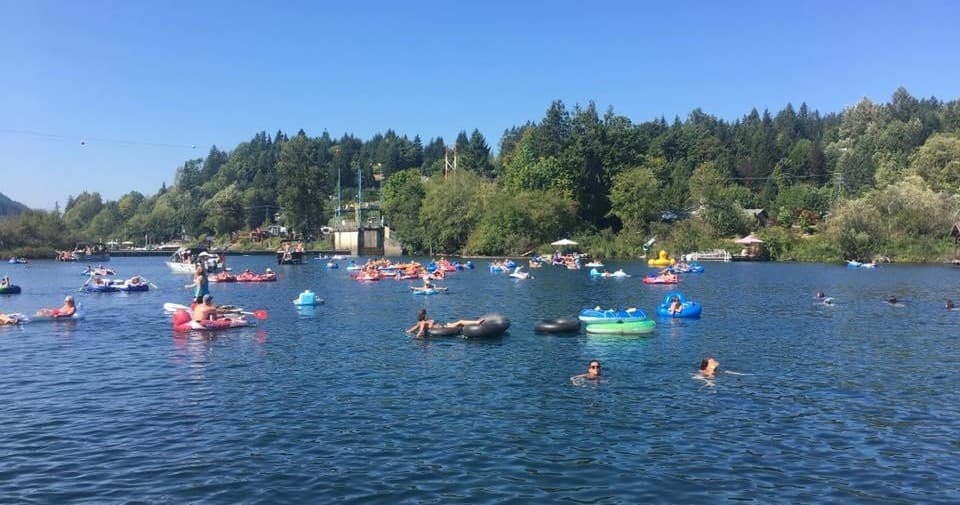Crowd of tubers floating on sunny Lake Cowichan shoreline
