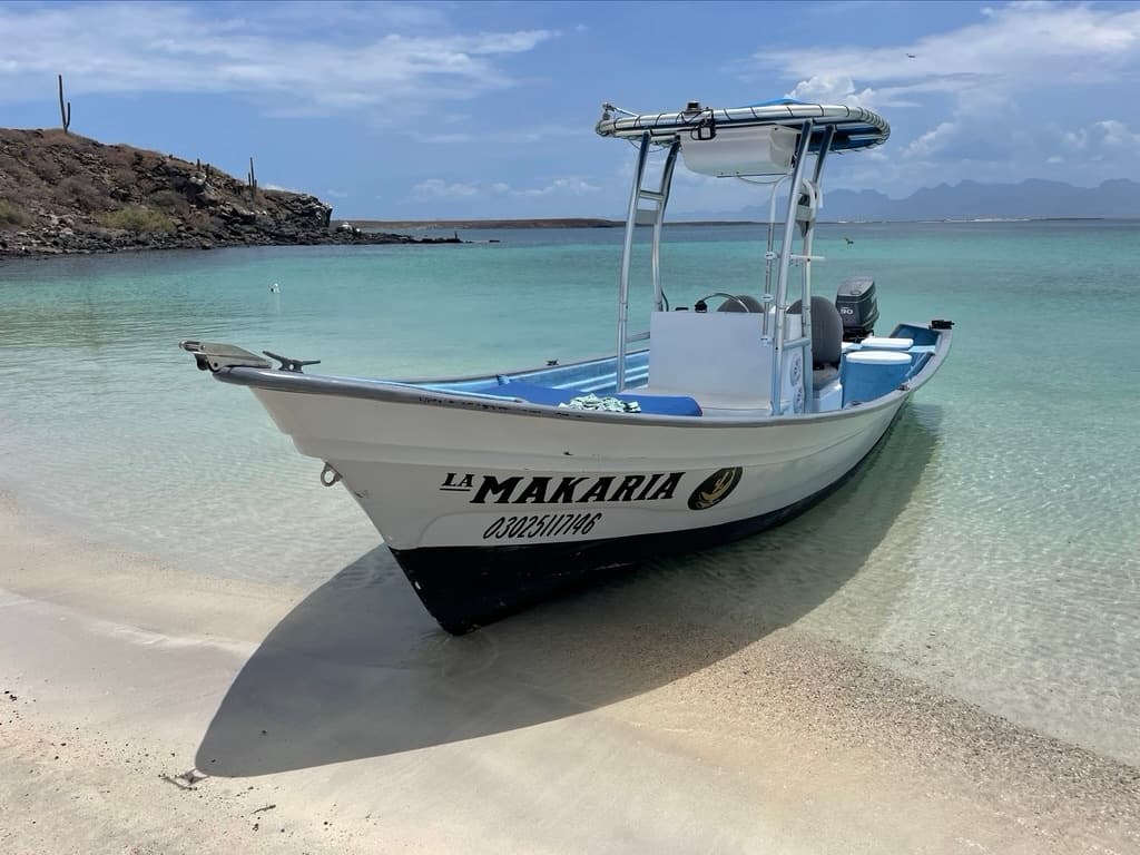 Small fishing boat beached on clear sand with turquoise water