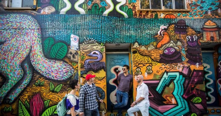 People gathered by colorful urban graffiti on Montreal tour