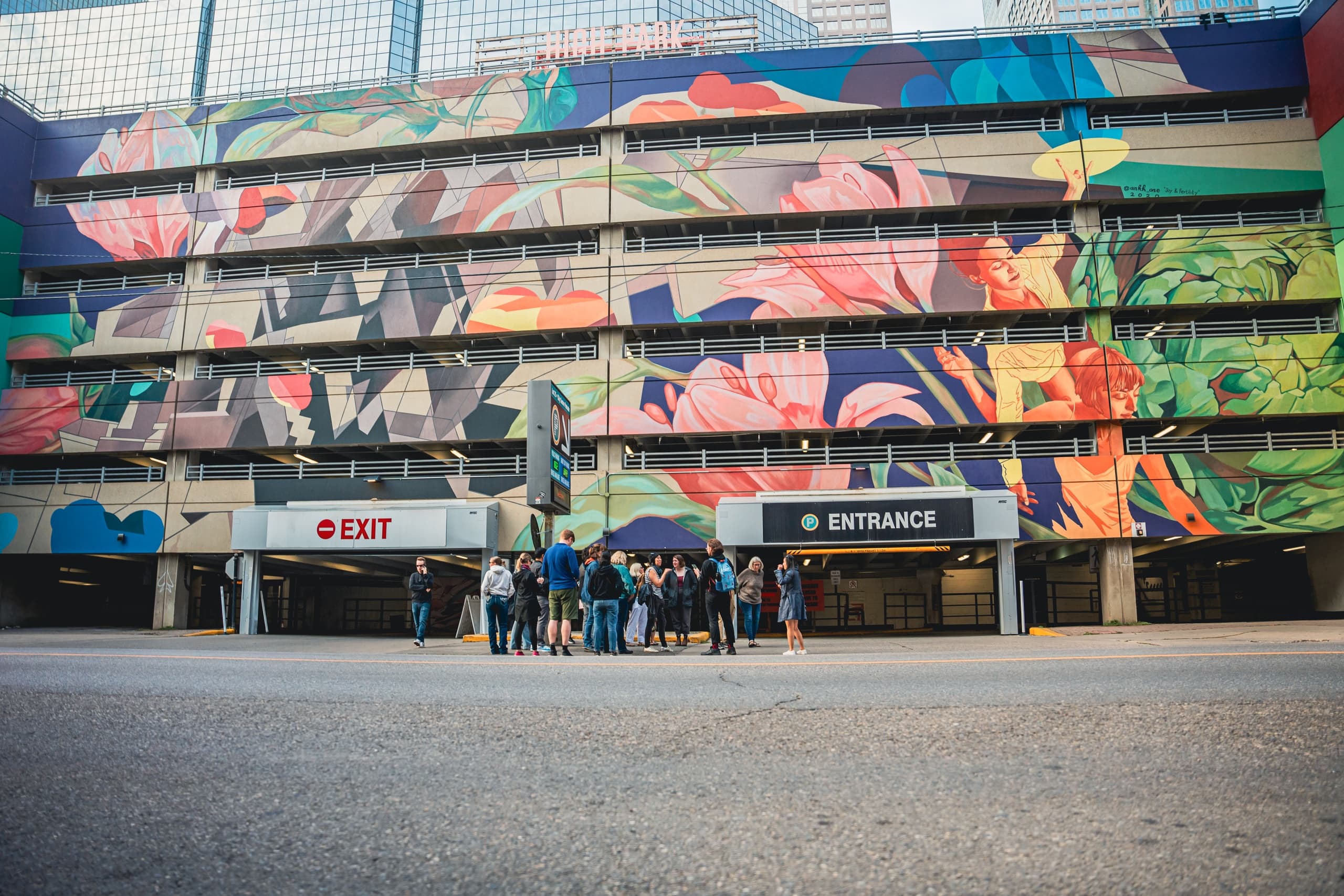Urban mural-covered parking garage with tour group on street