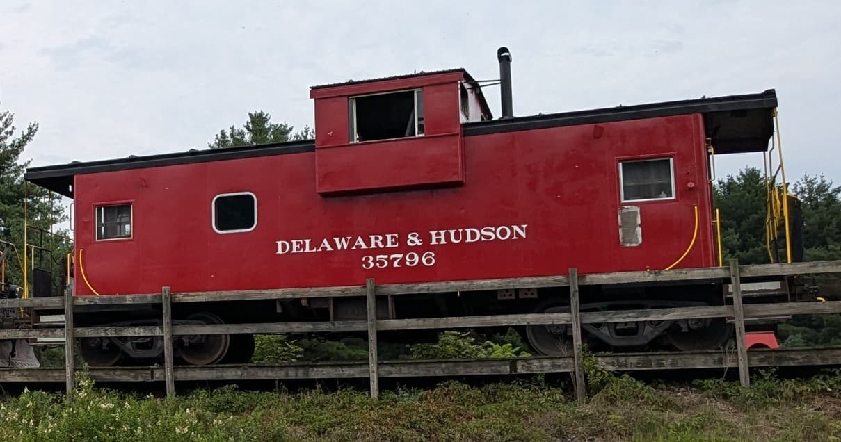 Red caboose on rural track at Cooperstown & Charlotte Valley Railroad