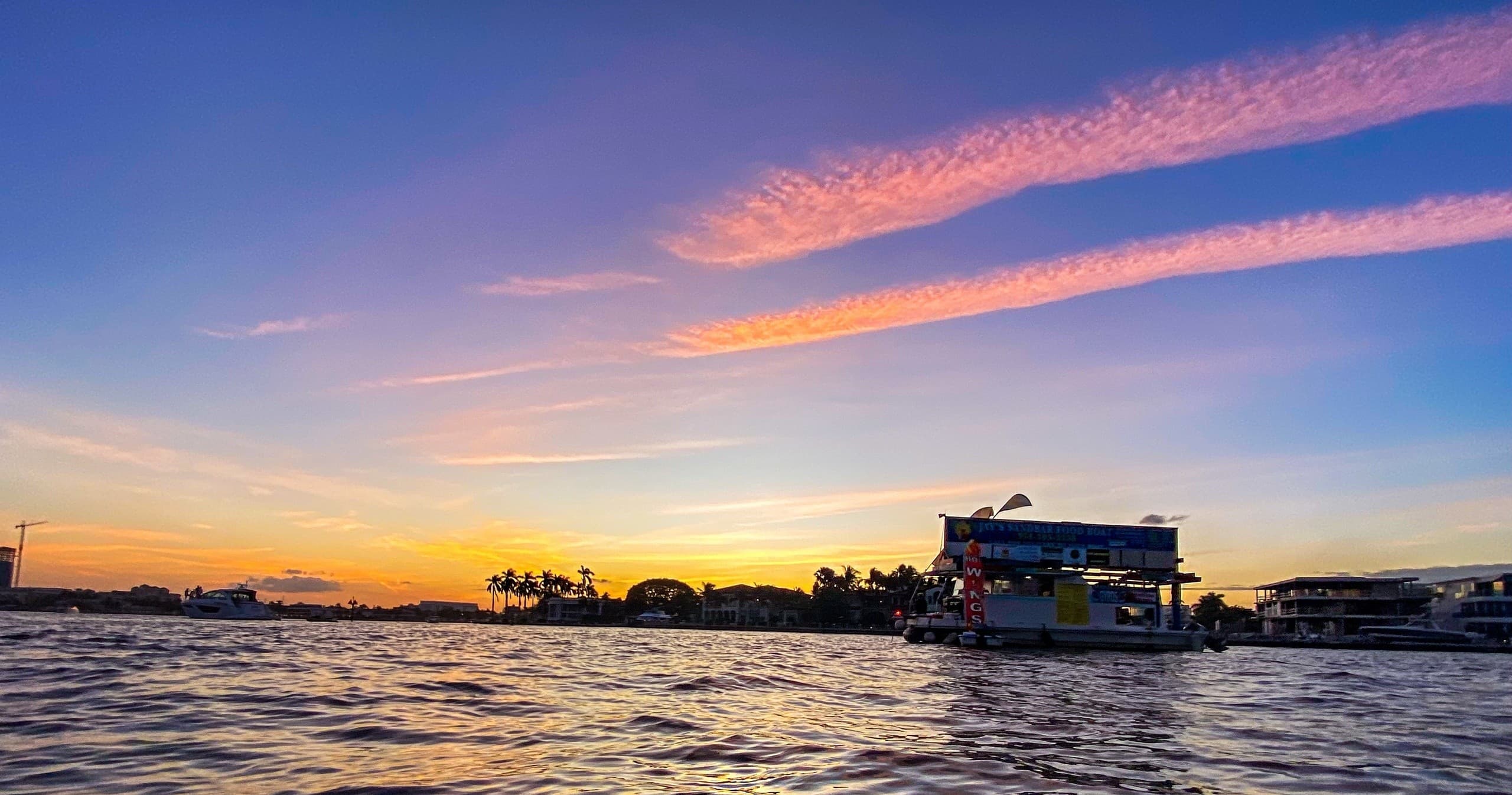 Sunset boat cruising near coastline with vibrant sky panorama