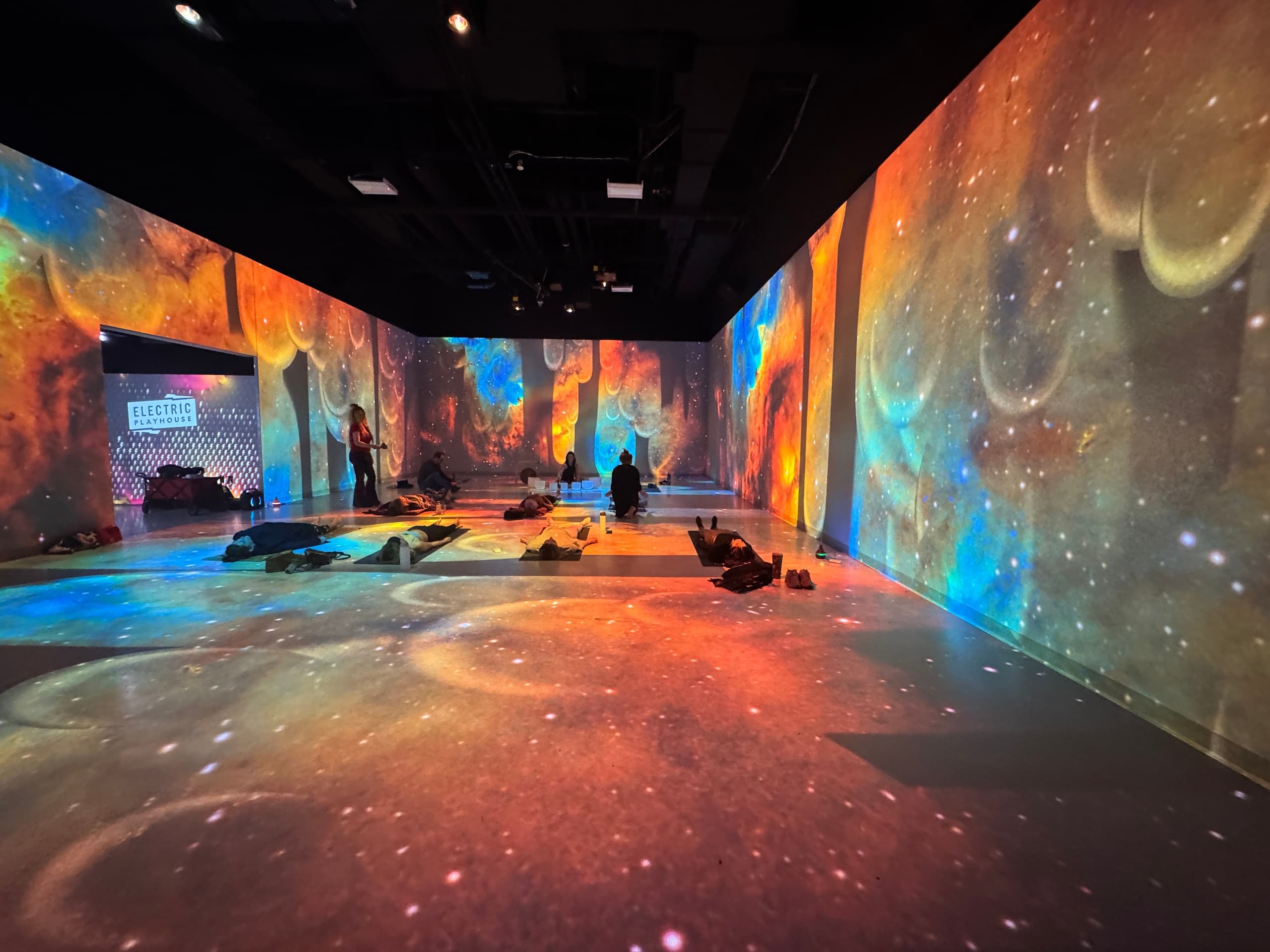 Immersive cosmic projection room with visitors lounging