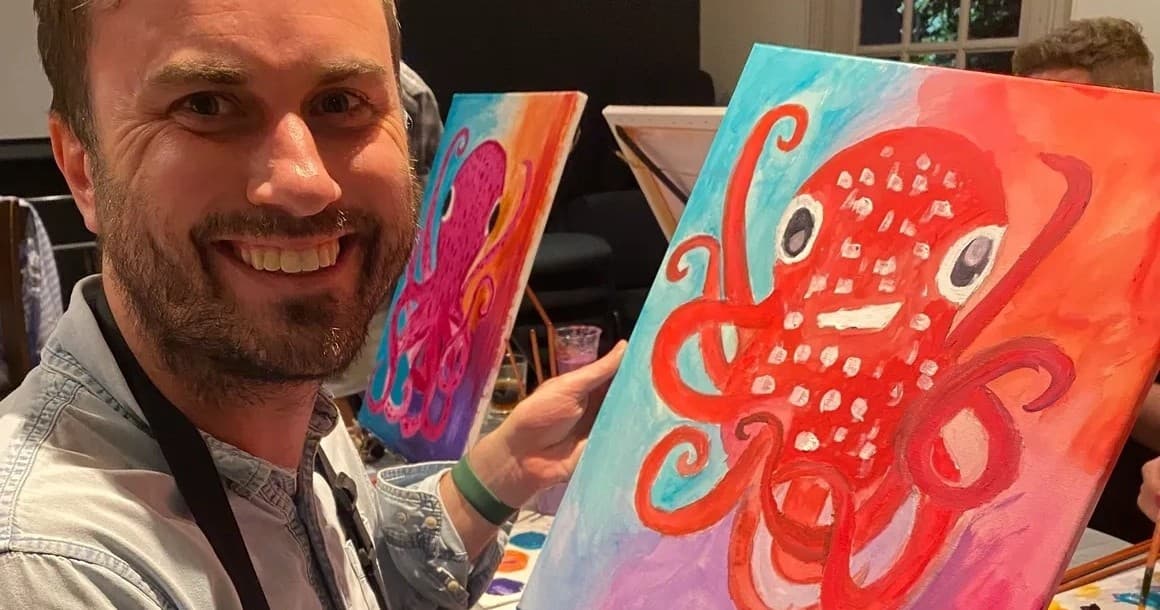 Man painting an octopus canvas at an indoor art party event