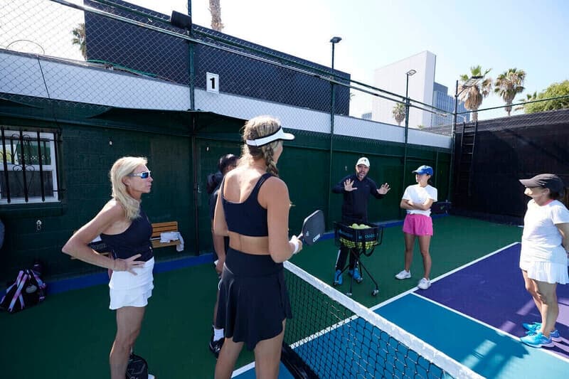 Pickleball coaching session outdoors on green court with players
