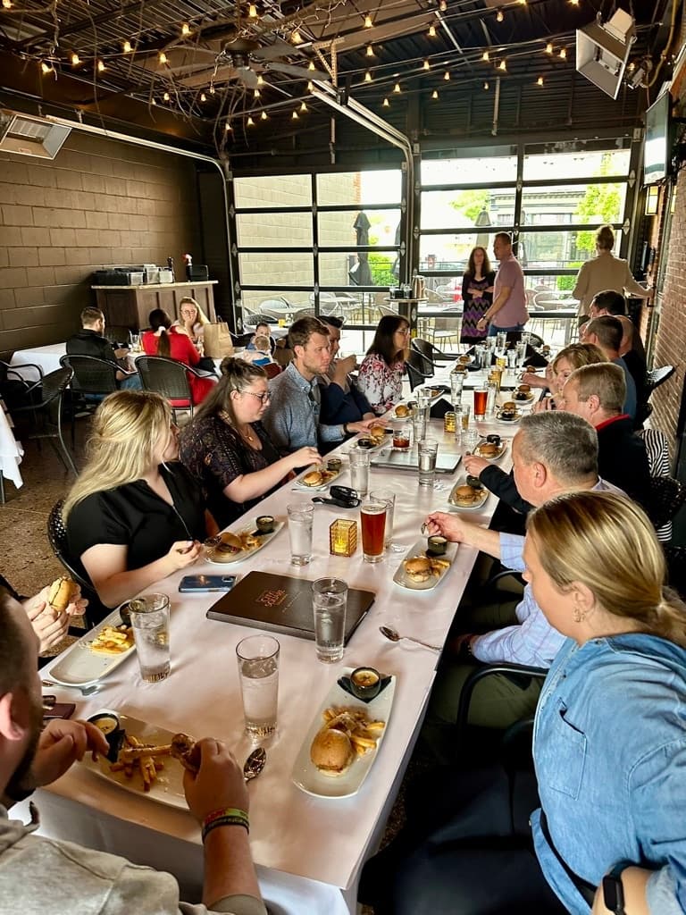 Group dining in open garage-style restaurant with patio view