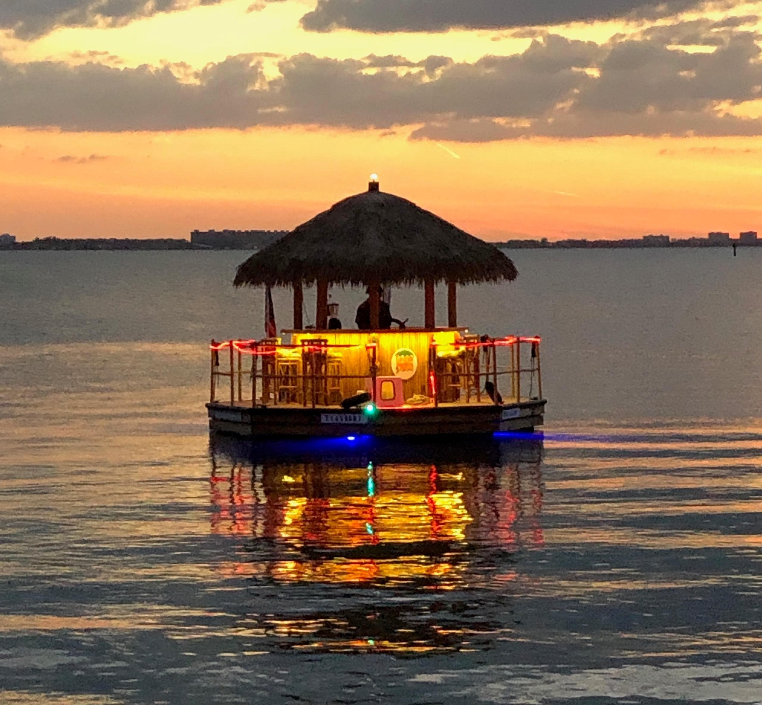 Sunset floating tiki bar reflecting over Sarasota bay during golden hour