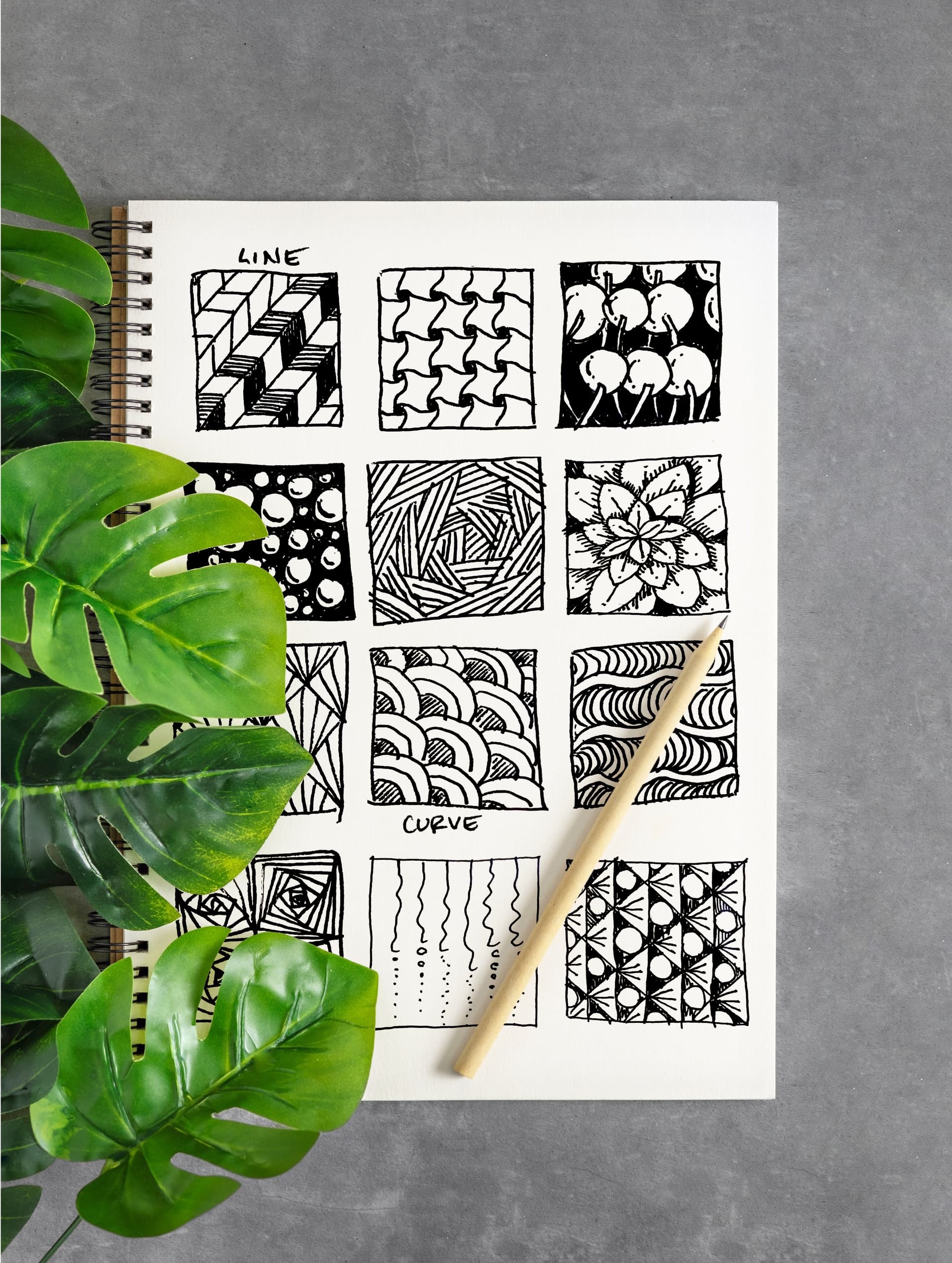 Zentangle ink pattern sketchbook photographed with tropical leaf props