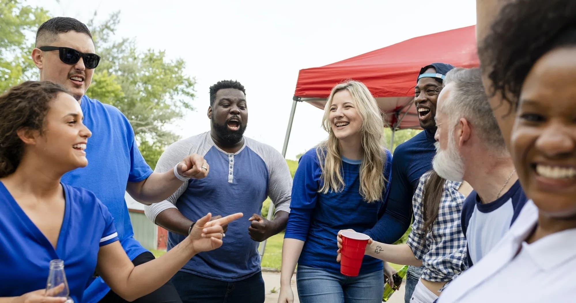 Friends socializing at outdoor tailgate party under trees
