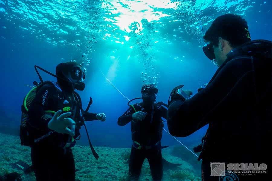 Group scuba lesson underwater with instructor in clear sea