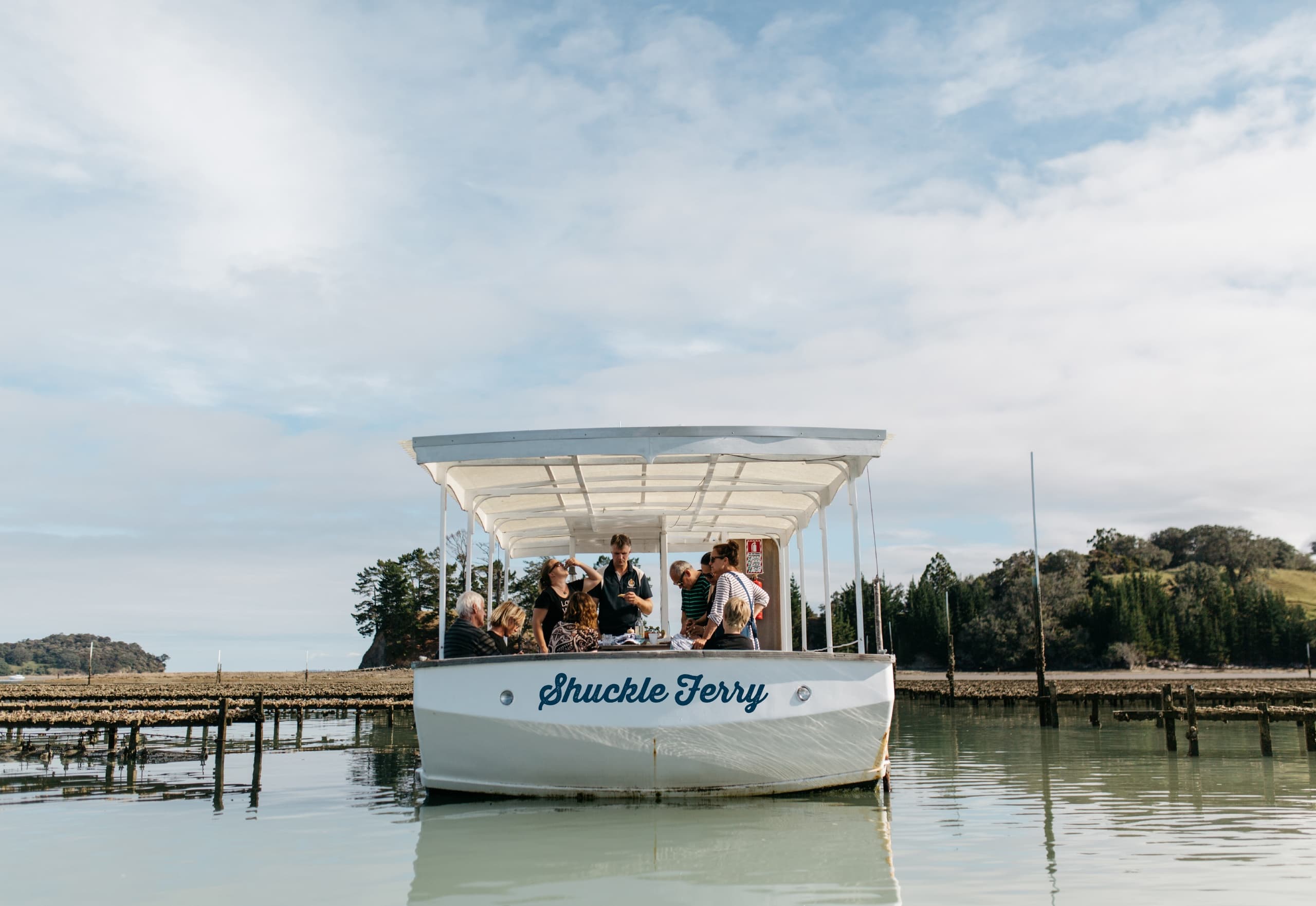 Oyster ferry carrying guests across calm estuary near oyster beds