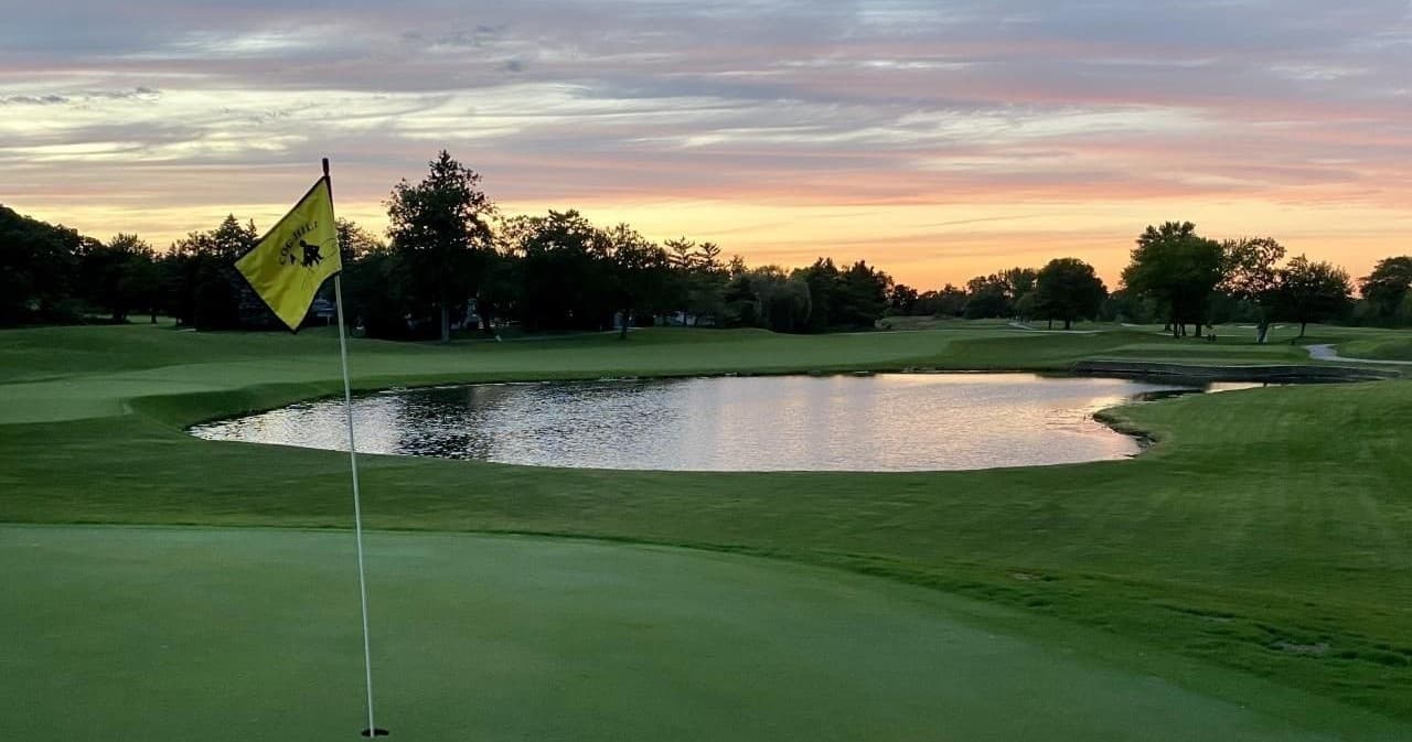 Sunset golf course fairway with water hazard and flag