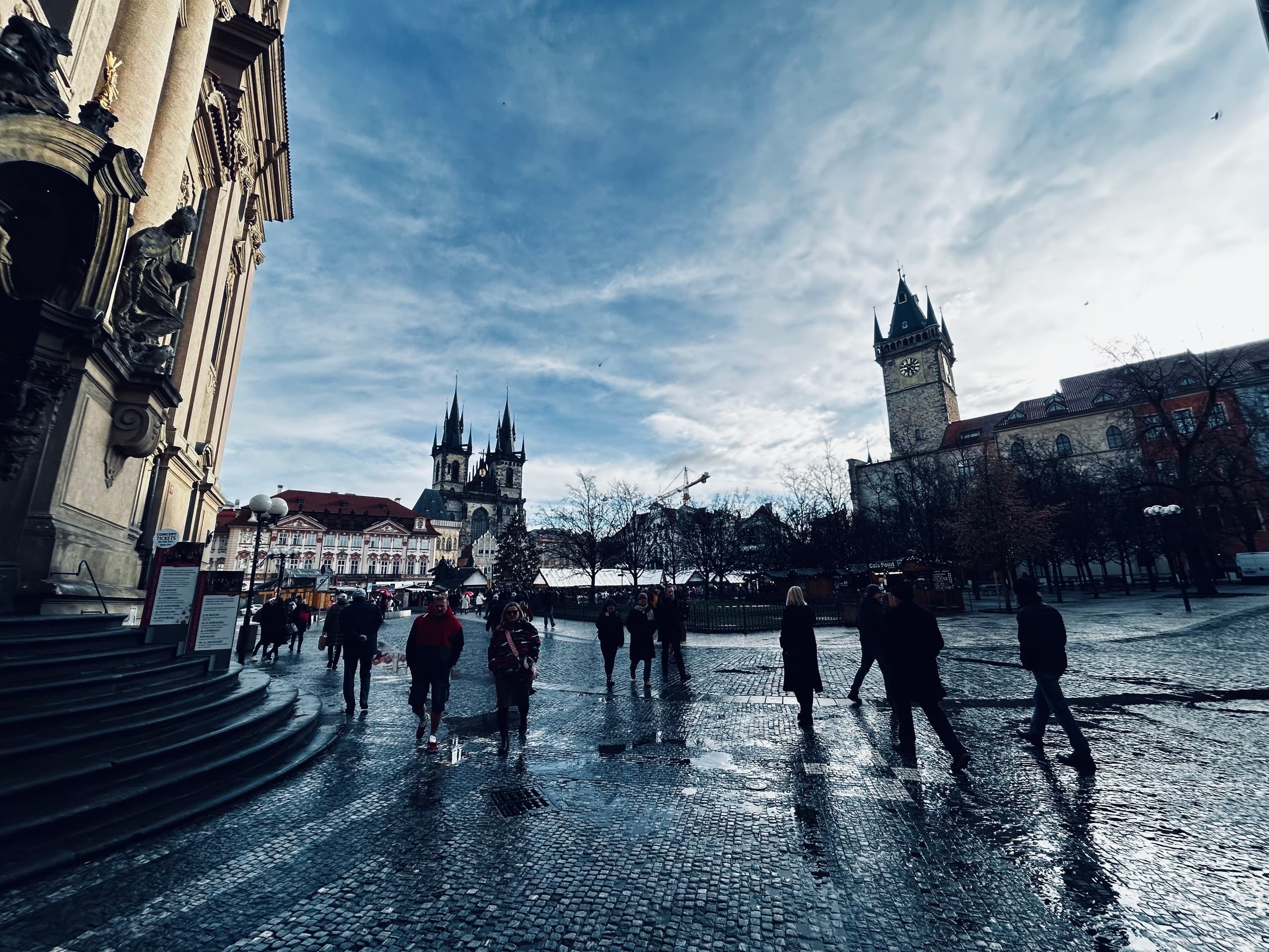 Crowds in historic Old Town Square under dramatic cloudy sky