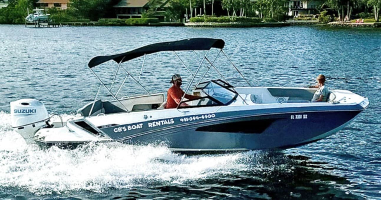 Speedboat cruising coastal waters near shoreline, passengers onboard